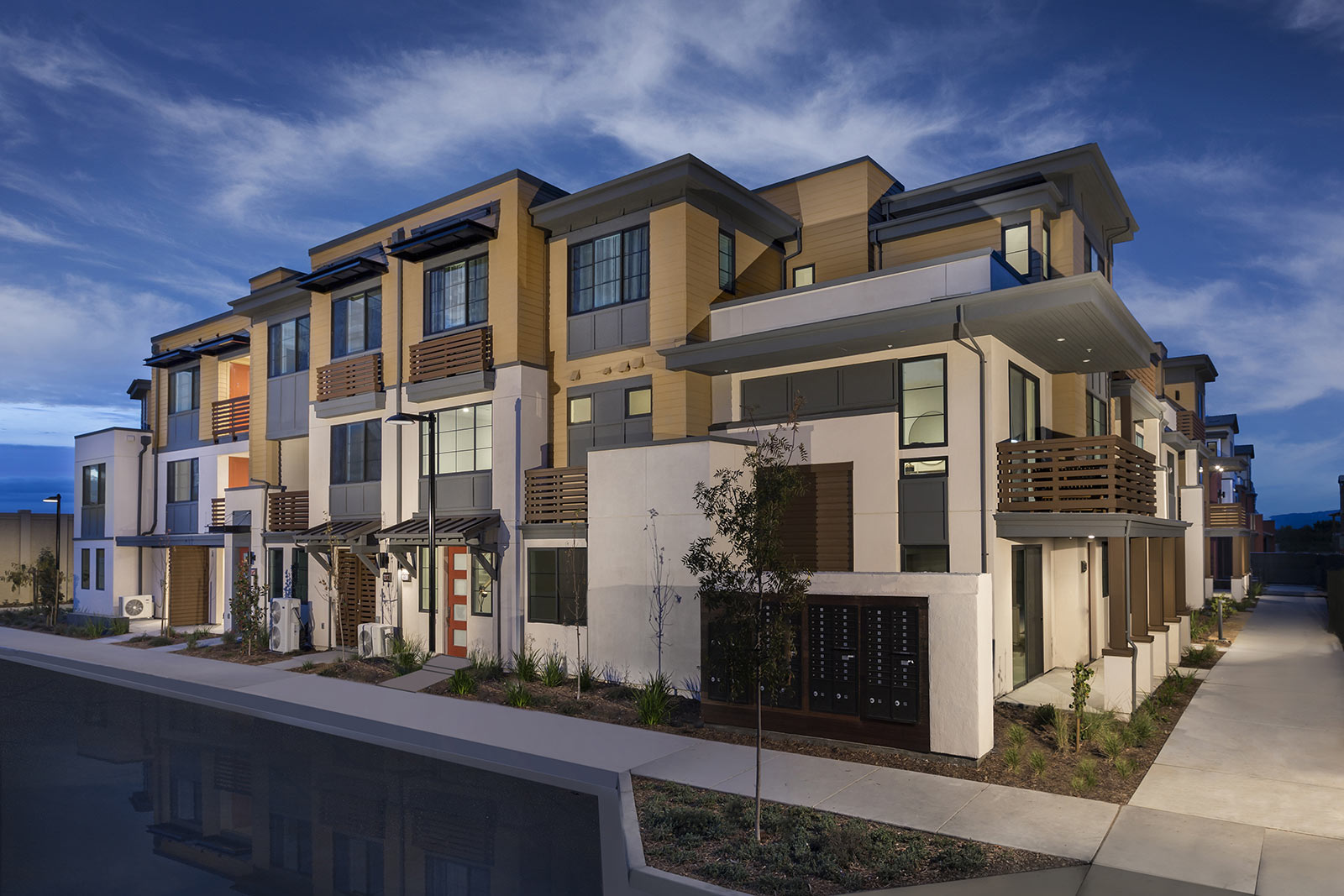 Modern multi-story townhouses by SummerHill Homes at dusk.