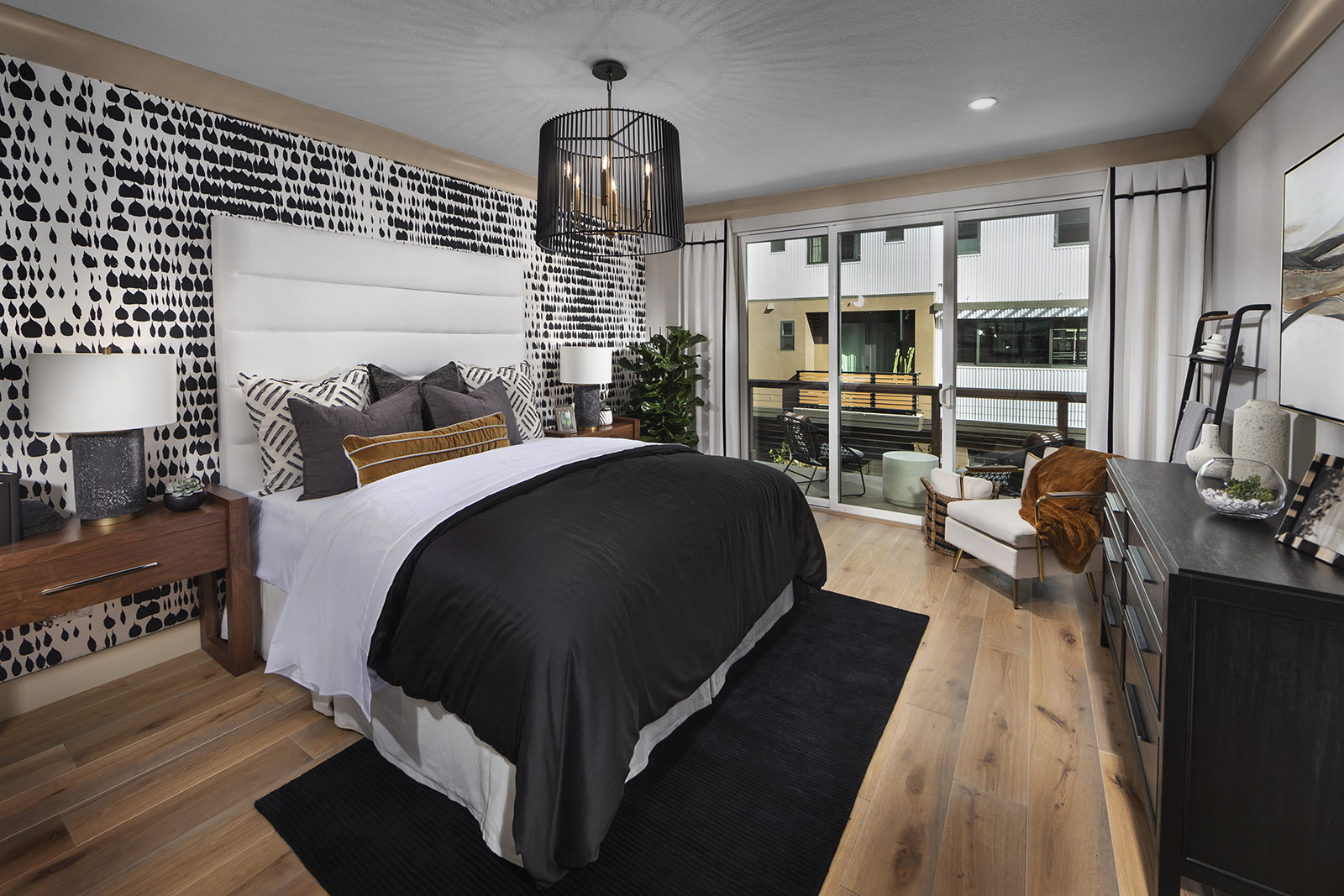 Modern bedroom by SummerHill Homes with accent wall, large bed, and balcony access.