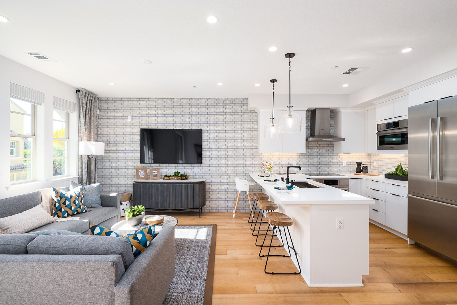 Chic open-concept living space by SummerHill Homes featuring a modern kitchen, cozy lounge area, and elegant pendant lighting.