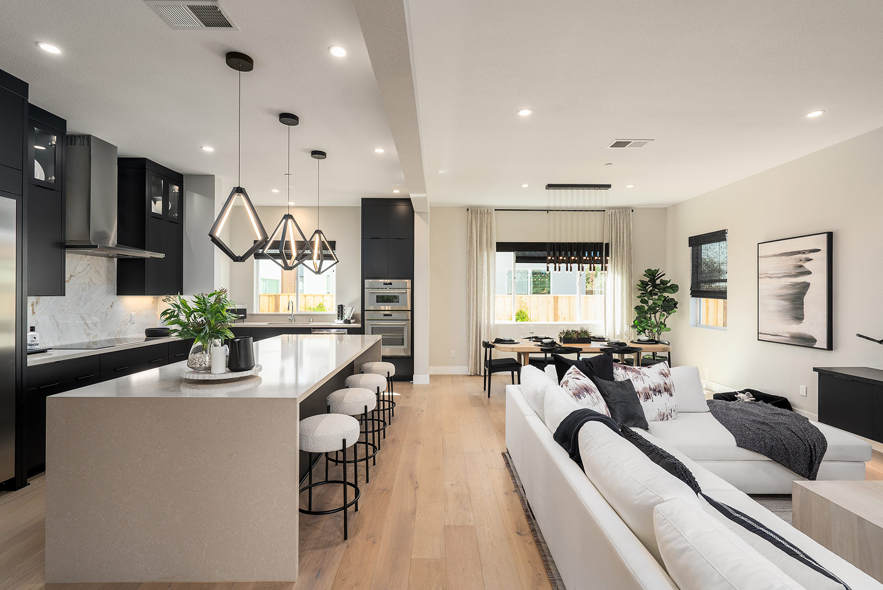 Spacious open-concept kitchen and living area by SummerHill Homes, featuring a large island with seating, modern appliances, and elegant lighting.