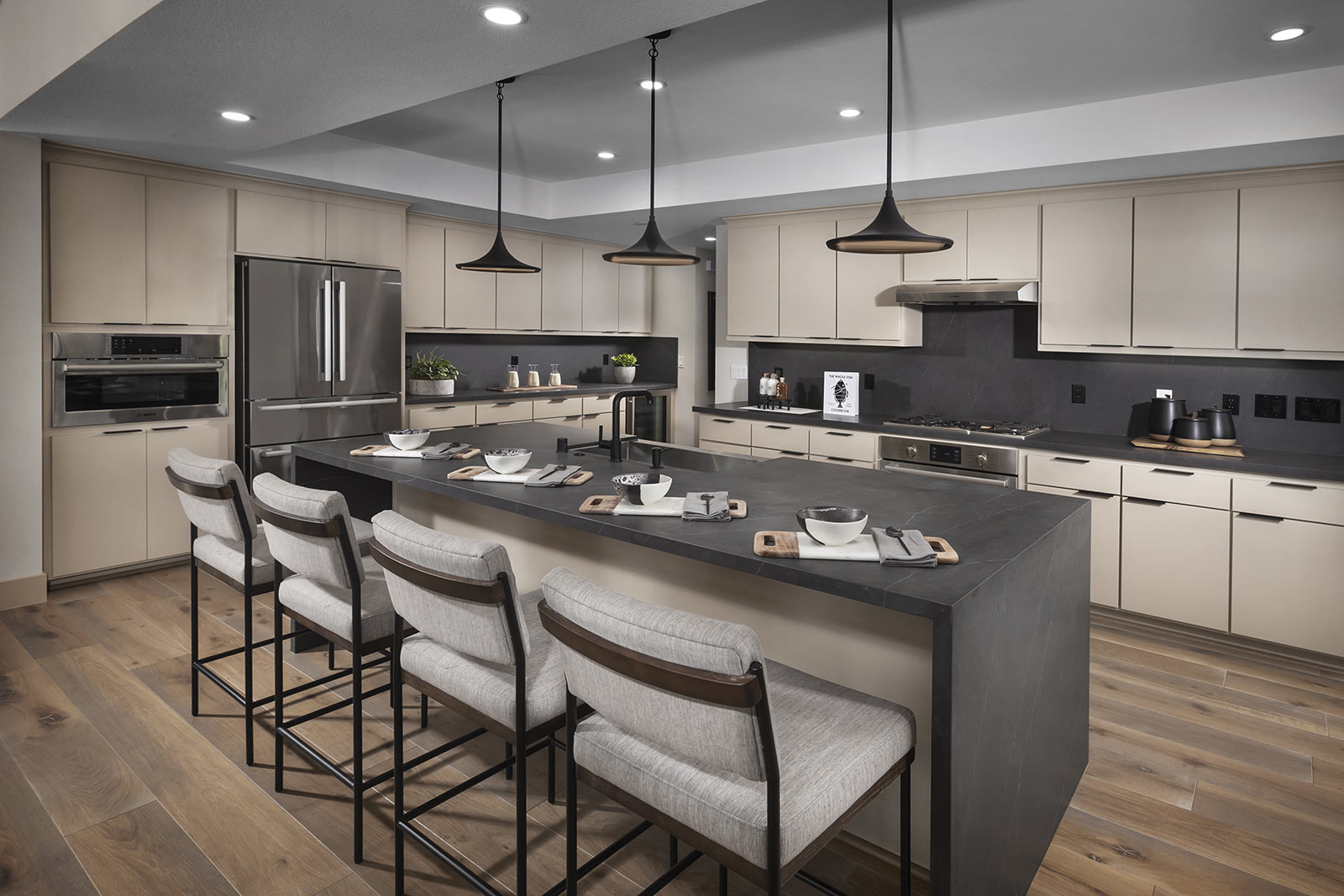 Elegant kitchen by SummerHill Homes featuring a large island with seating, sleek cabinetry, and modern pendant lighting.